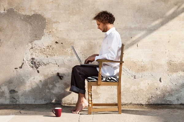 Portrait d'un jeune homme sur un mur, avec ordinateur portable — Photo