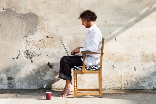 Portrait d'un jeune homme sur un mur, avec ordinateur portable — Photo