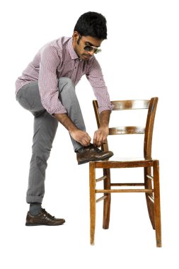 genç adam dizeleri bir sandalyeye bağlar.