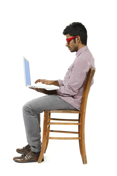 Retrato de hombre joven trabajando con el ordenador portátil sentado en una silla — Foto de Stock