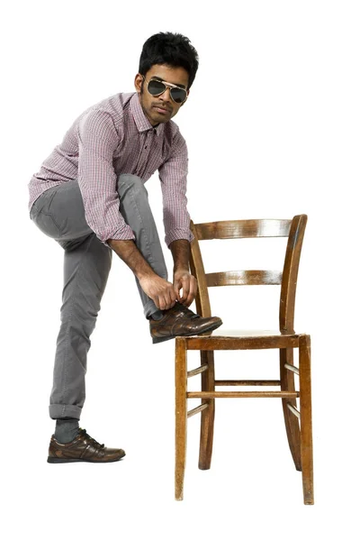 Jonge man banden tekenreeksen op een stoel — Stockfoto