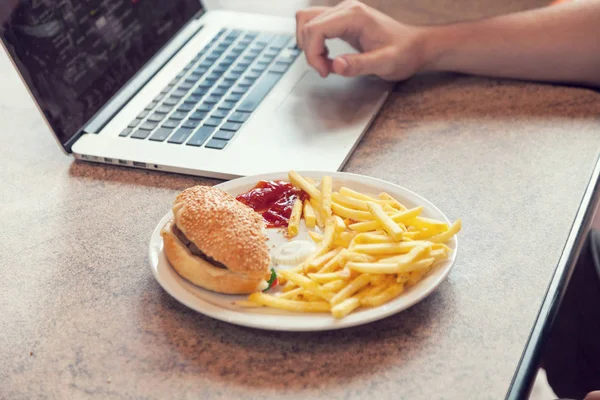 Ноутбук с обедом, гамбургером и французскими чипсами — стоковое фото