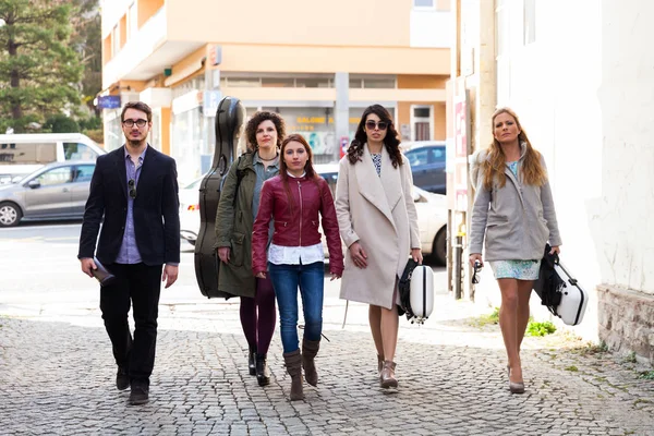 five musicians walk along the avenue