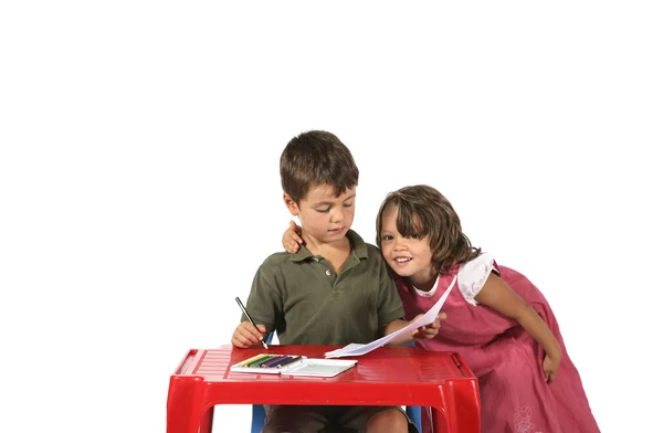 Grundschulkinder am kleinen roten Schreibtisch — Stockfoto