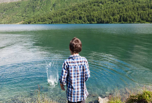 Little boy on the bank of mountain lake — Stock Photo, Image