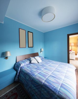 Duvardaki çerçeveli mavi yatak odası