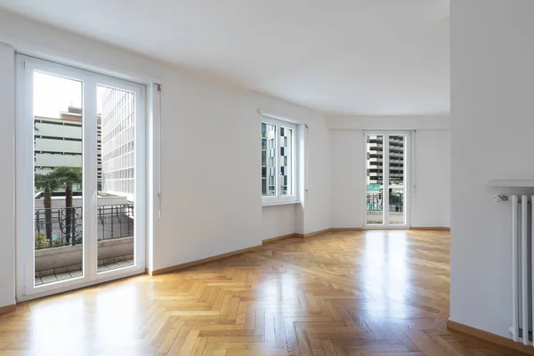 Habitación vacía en un apartamento con paredes blancas y suelos de madera — Foto de Stock