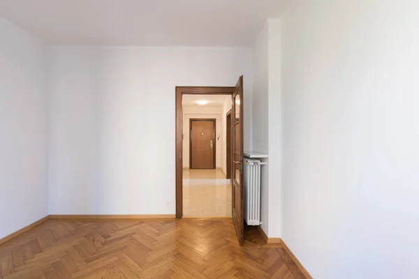 Quarto vazio em um apartamento com paredes brancas e pisos de madeira — Fotografia de Stock