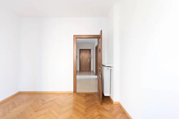 Habitación vacía en un apartamento con paredes blancas y suelos de madera — Foto de Stock