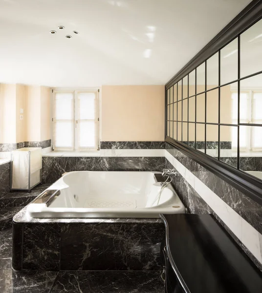 Badezimmer mit schwarzen Marmorfliesen und leerer großer Badewanne — Stockfoto