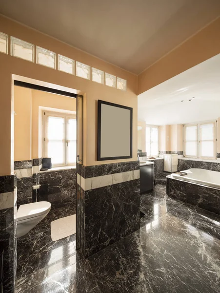 Badezimmer mit schwarzen Marmorfliesen und leerer großer Badewanne — Stockfoto