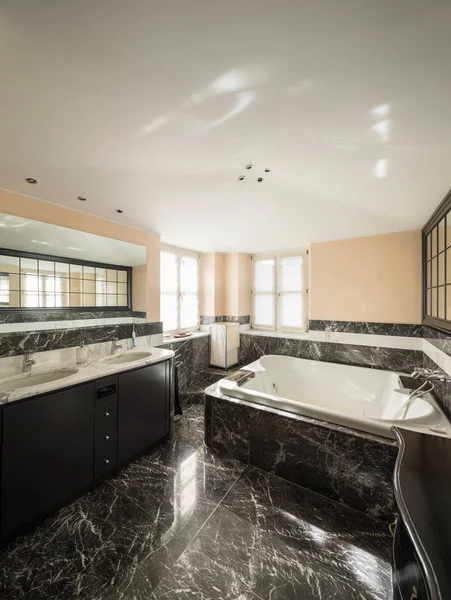 Badkamer met zwart marmeren tegels en leeg grote bad — Stockfoto
