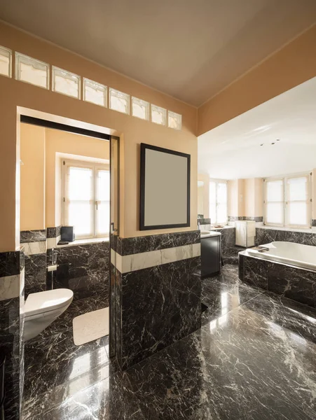 Bathroom with black marble tiles and empty big bathtub — Stock Photo, Image