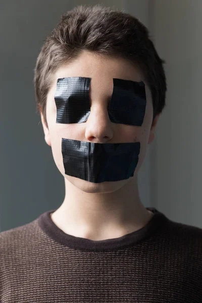 Boy with tape on the mouth and eyes