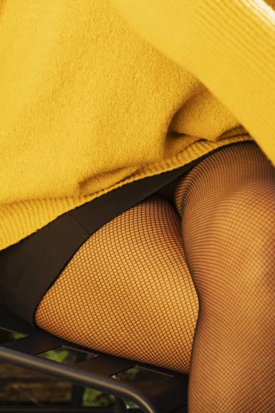 Detal kobiecych nóg z żółtym swetrem, czarną minispódnicą i — Zdjęcie stockowe