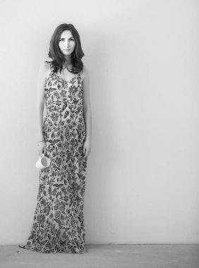 Beyaz bir duvara karşı duran güzel bir kadın. Siyah beyaz fotoğraf.