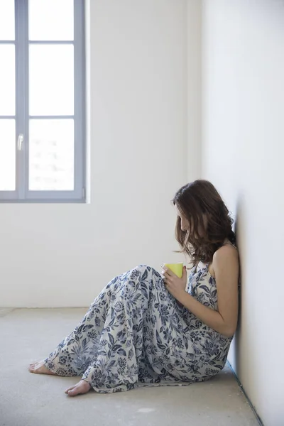 Donna Seduta Terra Una Stanza Vuota Con Una Tazza Mano — Foto Stock