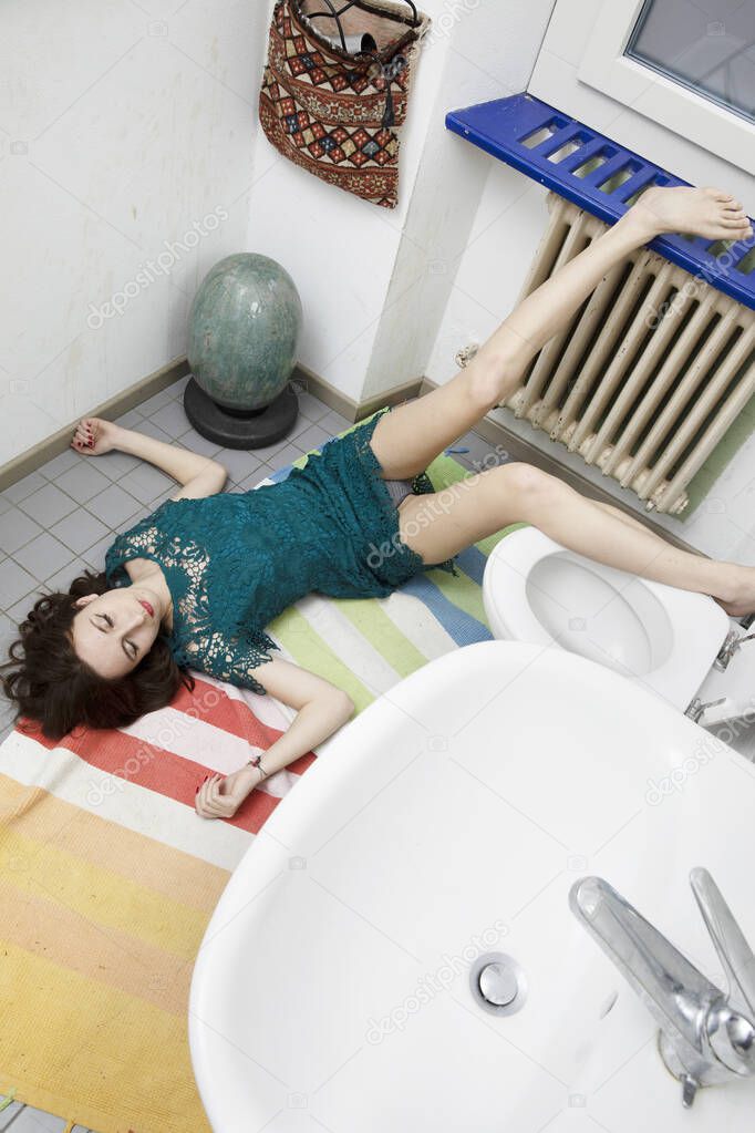 Young woman lying in the bathroom after a bad fall, typical domestic accident situation