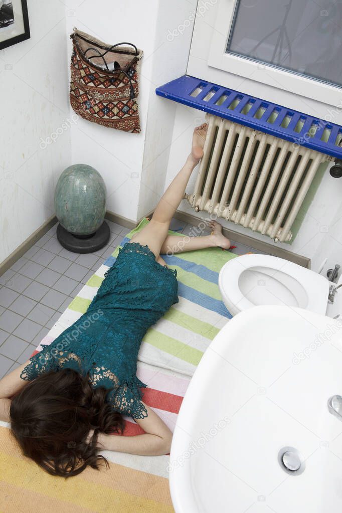 Young woman lying in the bathroom after a bad fall, typical domestic accident situation