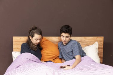 Yatakta bir çift telefonda film ya da haber izliyor..