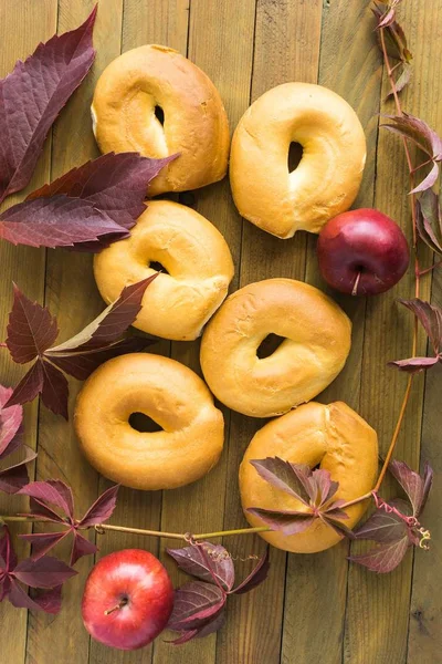 Bagels, apples and autumn leaves on a wooden table — Stock Photo, Image