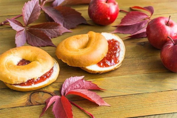 Bagels with raspberry jam, apples and autumn leaves — Stock Photo, Image