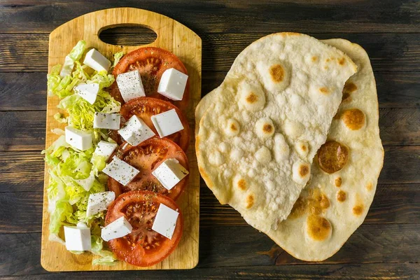 düz ekmek silindir Mini değirmenler ve ahşap bir masa üzerinde keçi peyniri salatası