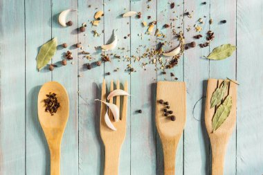 Ahşap mutfak gereçleri ve eski bir tablo üzerinde çeşitli baharatlar