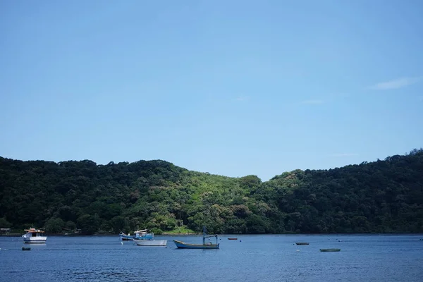 Bertioga Brezilya 'ya yakın küçük bir nehirde bir balıkçı teknesi duruyor güneşli bir günde yeşil ormanlı tepelerden önce, vahşi yaşam