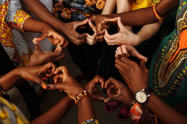 Mãos na forma do coração do grupo feliz de pessoas africanas, latino-americanas e europeias multinacionais que permanecem em círculo — Fotografia de Stock