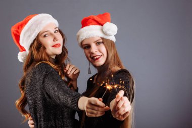 Çekici, neşeli, uzun kıvırcık saçlı, Noel şapkalı kızlar.