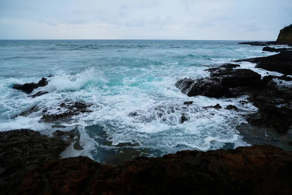 Deniz kenarındaki dalgalar fırtınalı bir günde kayalara sıçrıyor.