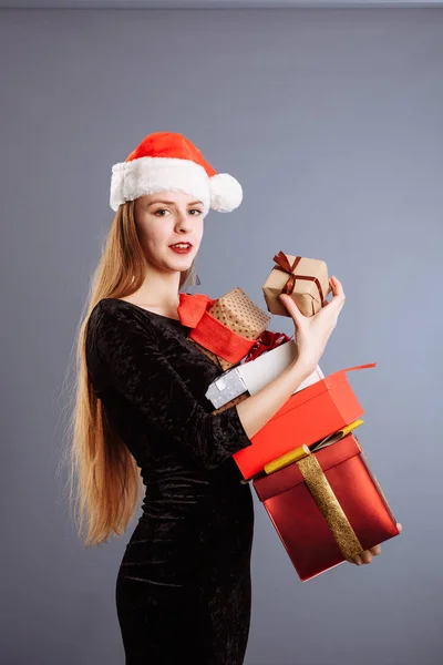 Beautiful European girl in a dress and Santa hat is catching big gift — Stock Photo, Image