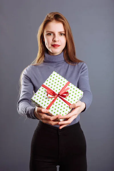 Uzun saçlı beyaz bir bayan sana ve bana gri arka planda izole edilmiş bir hediye kutusu veriyor...