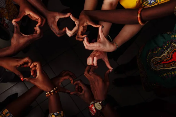 Ruce v podobě srdce šťastné skupiny nadnárodních afrických, latinskoamerických a evropských lidí, kteří zůstávají spolu v kruhu — Stock fotografie