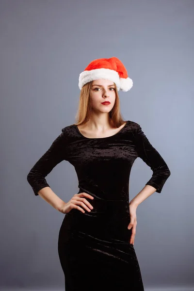 Retrato de mulher bonita alegre em chapéu vermelho de Papai Noel sorrindo isolado em fundo cinza. Menina bonita olhando feliz e animado. Feliz Natal e feriados de Ano Novo cheios de diversão . — Fotografia de Stock