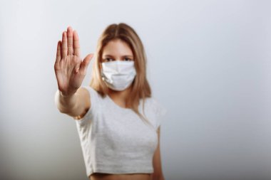 Yüz maskeli kadın virüslerin yayılmasını önlemek için dur işaretini eliyle gösteriyor. Seçici odak.