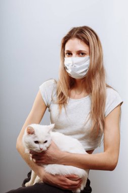 Koruyucu cerrahi maske takan kadın kedi yüzlü bir maske takıyor. Çin Coronavirüs Hastalığı COVID-19 evcil hayvanlar için tehlikelidir.