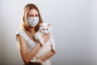 Koruyucu cerrahi maske takan kadın kedi yüzlü bir maske takıyor. Çin Coronavirüs Hastalığı COVID-19 evcil hayvanlar için tehlikelidir.