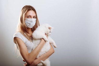 Koruyucu maskeli kadın kedi besliyor. Coronavirus hastalığı COVID-19 evcil hayvanlar için tehlikelidir