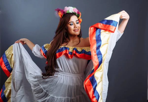 Gri arka planda geleneksel Kolombiya dansı yapan güzel bir kadın.
