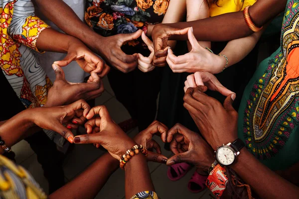 Hände in Herzform einer fröhlichen Gruppe multinationaler afrikanischer, lateinamerikanischer und europäischer Menschen, die im Kreis zusammenbleiben — Stockfoto
