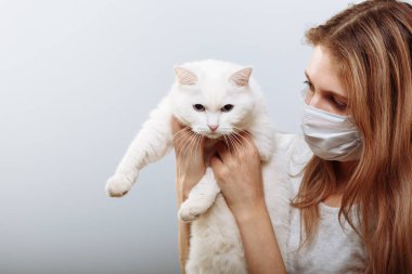 Koruyucu cerrahi maske takan kadın kedi yüzlü bir maske takıyor. Çin Coronavirüs Hastalığı COVID-19 evcil hayvanlar için tehlikelidir.