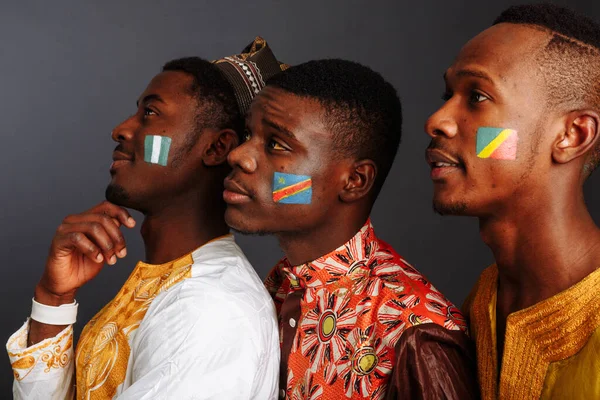 Concept of friendship between African countries: 3 American men in national clothes from different countries stay hug together with flags of Democratic Republic Congo, Republic of the Congo, Nigeria