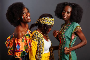 Üç güzel Afrikalı model geleneksel kıyafetlerle eğleniyor ve gülüyor. Kongo Cumhuriyeti, Fildişi Sahili ve Zimbabwe kadınları.