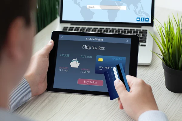 Чоловік тримає планшетний комп'ютер онлайн судновий квиток і кредитну картку — стокове фото