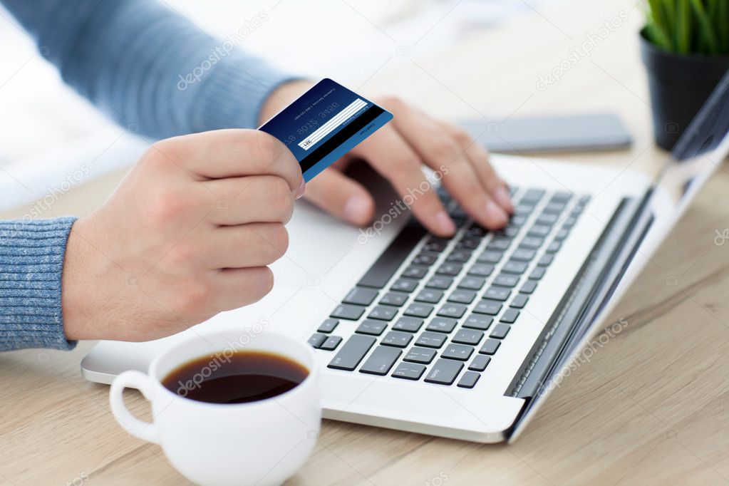 men hands with credit card on laptop keyboard and coffee
