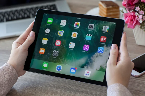 Donna che tiene iPad Pro spazio grigio con carta da parati IOS 10 — Foto Stock