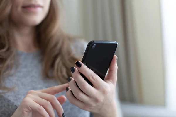 Donna che tiene in mano il telefono tattile nero — Foto Stock