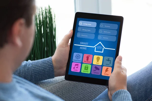 Man sitting on sofa holding tablet computer app smart home — Stock Photo, Image